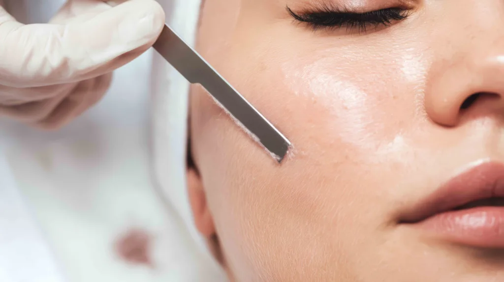 The science of dermaplaning, an enhanced cosmetic esthetics treatment to exfoliate your skin, making you look younger, and more vibrant. A licensed esthetician at Panache Day Spa in Meridian uses a small blade to gently exfoliate a woman's face in Meridian.