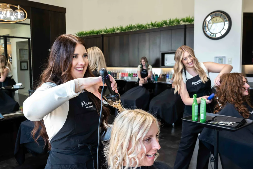 A busy hair salon that features hair color transformations, hair stylists doing routine haircare, haircuts, round brush blowouts, botanical hair therapy treatments, permanent waves, and more popular styles for the busy Meridian, Idaho back-to-school season! Visit Panache hair studio and day spa today! Book an appointment online. 