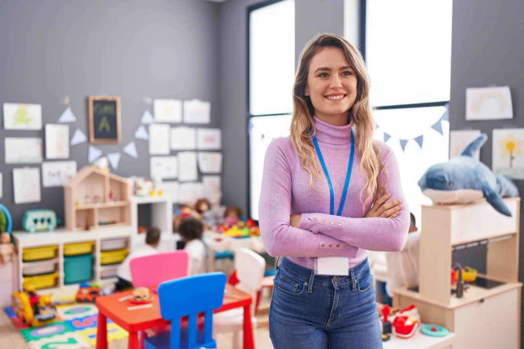 A young, blonde female elementary teacher, standing in her empty classroom. Back to school hairstyles and skincare from Panache Hair Studio in Meridian is making her look good, and feel even better.