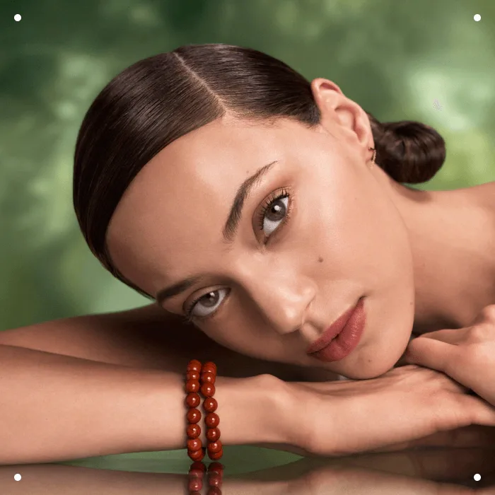 A beautiful model with brown hair and clear skin, resting her head on her hands. Showcasing the power of Aveda's plant-based skincare products and services offered by Panache in the Boise area. 